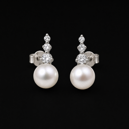 Trilogy white Freshwater pearl stud earrings with three cubic zirconia on a matte black background